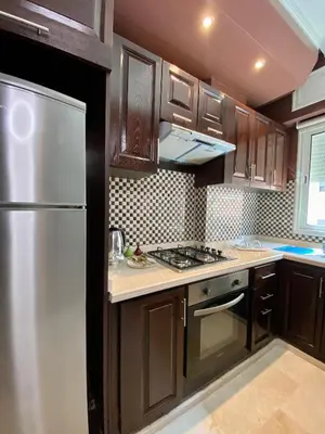 a kitchen with wooden cabinets and a stainless steel refrigerator at Appart Hôtel Oleandro in Casablanca