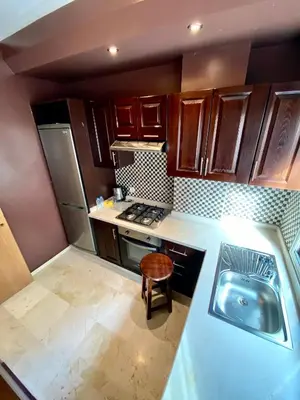 a small kitchen with wooden cabinets and a sink at Appart Hôtel Oleandro in Casablanca