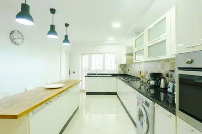 a white kitchen with white cabinets and black appliances at Beautiful Moroccan apartment Casablanca Center in Casablanca