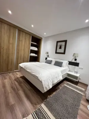 a bedroom with a large white bed and wooden floors at Central Holiday Apartment in Casablanca