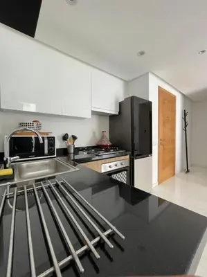 a kitchen with white cabinets and a black refrigerator at Central Holiday Apartment in Casablanca
