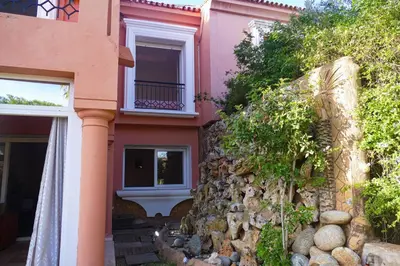 a pink house with a stone wall at Villa luxueuse au centre du golf in Bouznika