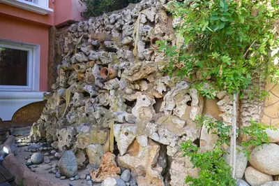 a stone wall with a garden in front of a building at Villa luxueuse au centre du golf in Bouznika
