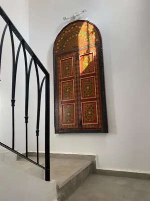 a large wooden door on a wall next to a staircase at Villa entière Dar Baida Plage David Bouznika in Bouznika