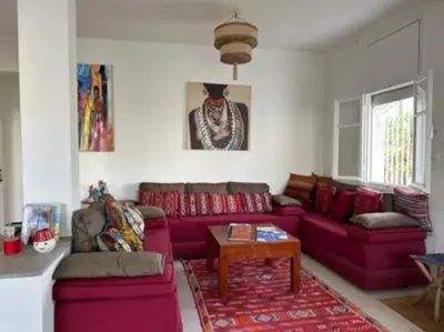 a living room with a red couch and a table at Villa entière Dar Baida Plage David Bouznika in Bouznika