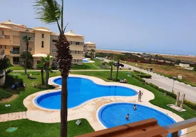 a view of a swimming pool with a palm tree at Appart Residence Haut Standing in Bouznika