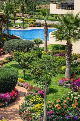 a garden with flowers and palm trees and a swimming pool at Appart Residence Haut Standing in Bouznika