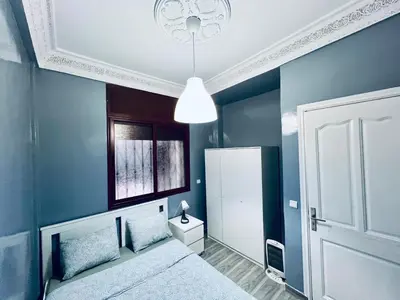 a blue bedroom with a bed and a white door at Appartement très équipé etpropre 1 in Camp de Mediouna