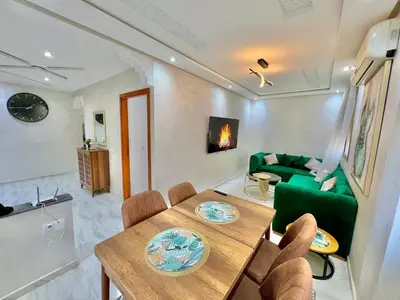a living room with a table and a green couch at A2 Luxe Moderne et Confort, 7 min du Stade Moulay Abdellah in Temara