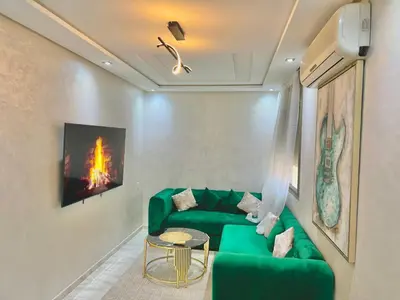 a living room with a green couch and a table at A2 Luxe Moderne et Confort, 7 min du Stade Moulay Abdellah in Temara