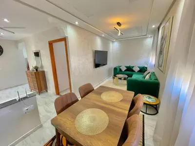 a living room with a table and a green couch at A2 Luxe Moderne et Confort, 7 min du Stade Moulay Abdellah in Temara