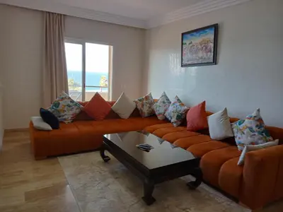 a living room with an orange couch and a table at Appart 3p vue sur mer in Rabat