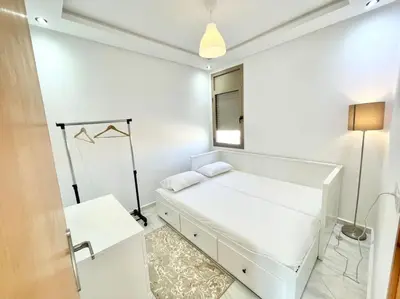a white bedroom with a bed and a window at A3 Luxe and Cosy Apartement, 7 min du Stade Moulay Abdellah in Temara