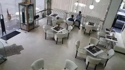 a room with white chairs and tables and a man standing in a room at High-End Apartment with Terrace in Val Fleuri, Maarif Casablanca, Ideal for Families & Business Travelers in Casablanca