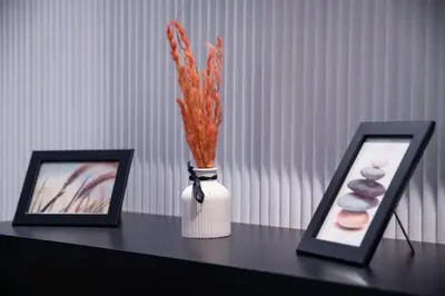 a table with a vase with carrots in it next to two pictures at Cosy & So Stylish Appartement Au coeur de Casablanca Bd 2 Mars Derrière Kfc 2 Min à Pieds vers Mcdo in Casablanca