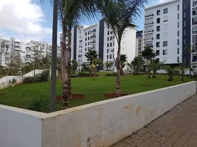 a park with palm trees in front of buildings at Studio à Prestigia HayRiad/Rabat in Rabat