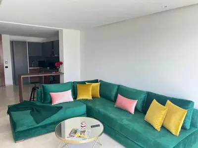 a green couch with yellow and pink pillows in a living room at Appartement CFC - Aeria mall in Casablanca