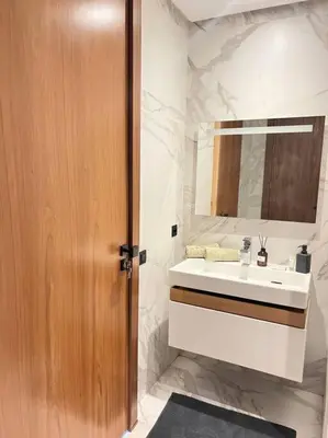 a bathroom with a sink and a wooden door at Appartement CFC - Aeria mall in Casablanca