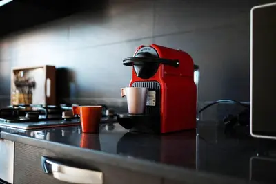 a red coffee machine sitting on a counter with cups at Beautifully Designed 3BR Apartment+ Panoramic View in Rabat