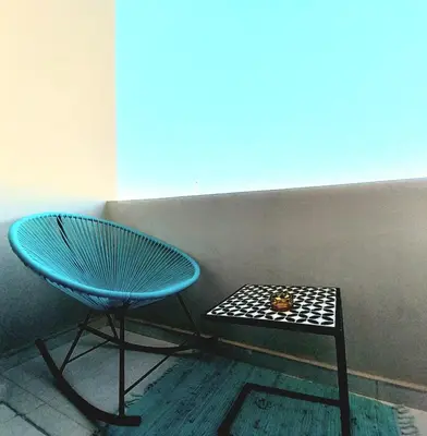 a blue chair and a table in a room at top apartment Airport Mohamed 5 in Derroua