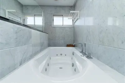 a white bath tub in a white tiled bathroom at Luxury villa Bouskoura Pearl in Casablanca