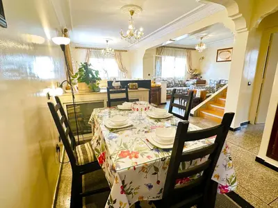 a dining room with a table with chairs and a kitchen at Spacieux et familial à 2 minutes à pied du stade de football de RABAT in Rabat