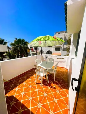 a table and chairs on a balcony with an umbrella at Spacieux et familial à 2 minutes à pied du stade de football de RABAT in Rabat