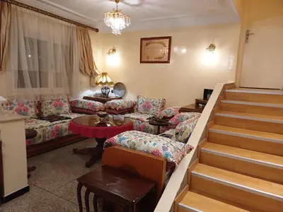 a living room with a couch and a stair case at Spacieux et familial à 2 minutes à pied du stade de football de RABAT in Rabat