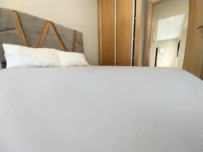 a large white bed with white pillows in a room at Airport mohamed 5 break apartments in Derroua