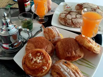 two plates of pastries on a table with orange juice at Airport mohamed 5 break apartments in Derroua