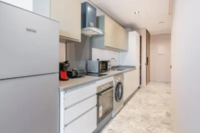 a kitchen with white cabinets and a washer and dryer at TTHOLIDAYS Cosy Apartment Casablanca City Center in Casablanca