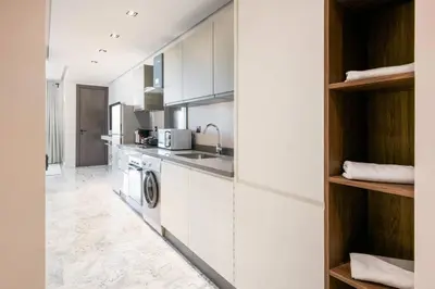 a kitchen with white cabinets and a washer and dryer at TTHOLIDAYS Cosy Apartment Casablanca City Center in Casablanca