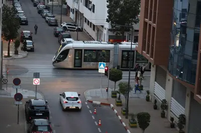 a train traveling down a city street with cars at Agdal 1 in Rabat