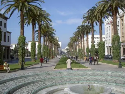 a group of people walking down a street with palm trees at Agdal 1 in Rabat