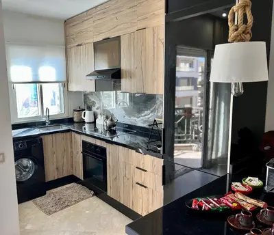a kitchen with wooden cabinets and a black counter top at Maarif , Cosy 2 Chambres, Parking wifi Netflix Gratuit in Casablanca
