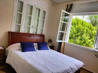 a bedroom with a bed with blue pillows and a window at Villa Pierrette Casablanca in Casablanca