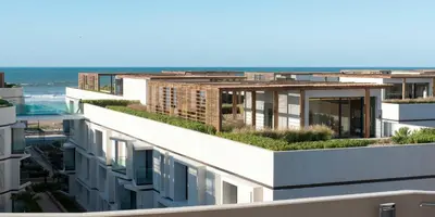an apartment building with a green roof with the ocean in the background at Ocean View Apartment - Anfa Place - in Casablanca