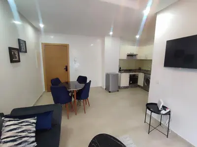 a living room with a table and blue chairs at Studio La gironde in Casablanca