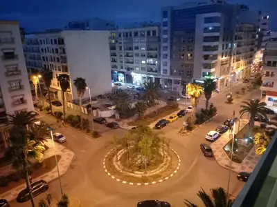 a city at night with cars parked in a parking lot at Appartement Parc Mohammedia in Mohammedia