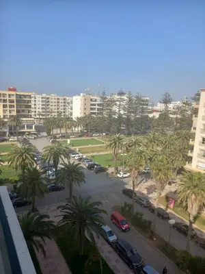 a view of a parking lot with palm trees and buildings at Appartement Parc Mohammedia in Mohammedia