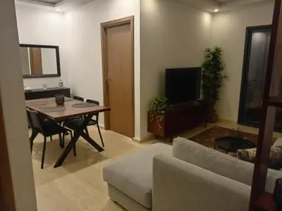 a living room with a table and a couch and a television at Appartement Parc Mohammedia in Mohammedia