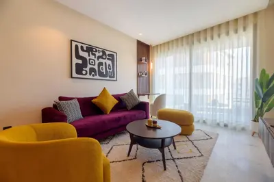 a living room with a purple couch and yellow chairs at Appartement luxueux et lumineux Maarif Casablanca in Casablanca