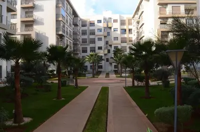 a walkway in front of a building with palm trees at New Luxury apartment 5 min Casablanca Mohammed V Airport in Casablanca