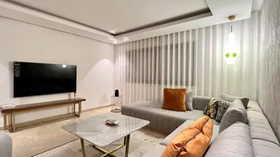 a living room with a couch and a flat screen tv at La Vida est Magnifique - 3 Chambres in Casablanca