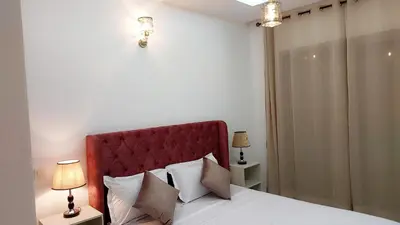 a bedroom with a bed with a red headboard and two lamps at Appartement Perla - Costa Bouznika in Bouznika