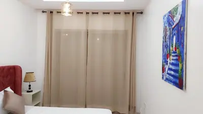 a bedroom with a shower curtain next to a bed at Appartement Perla - Costa Bouznika in Bouznika