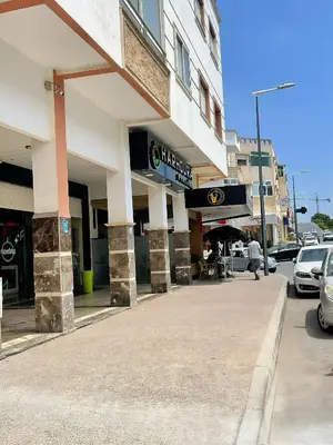 a building on a city street with cars parked outside at Résidence Ryad Albahr Herhoura in Temara