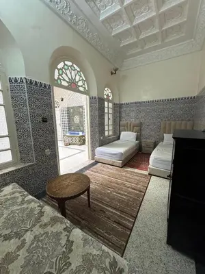 a bedroom with two beds and a table in a room at Riad Blue Garden in Rabat