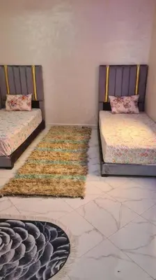 two beds in a room with two rugs at Rooms in shared apartment close to CMN-Airport in Dah Hammou Ben Cheïkh