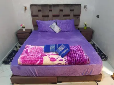 a bed with a purple comforter and two pillows at Rooms in shared apartment close to CMN-Airport in Dah Hammou Ben Cheïkh
